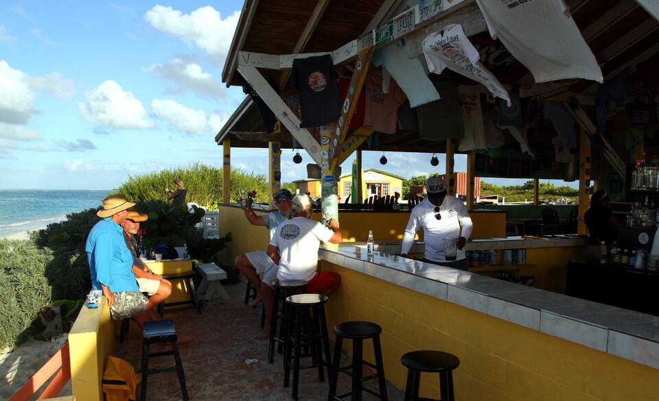 The Cow Wreck Beach Bar, Anegada: an open-air bar under a thatched roof, the beach behind