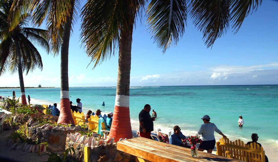 Cow Wreck Beach from the bar: palms, picnic tables and swimmers in shallow turquoise water