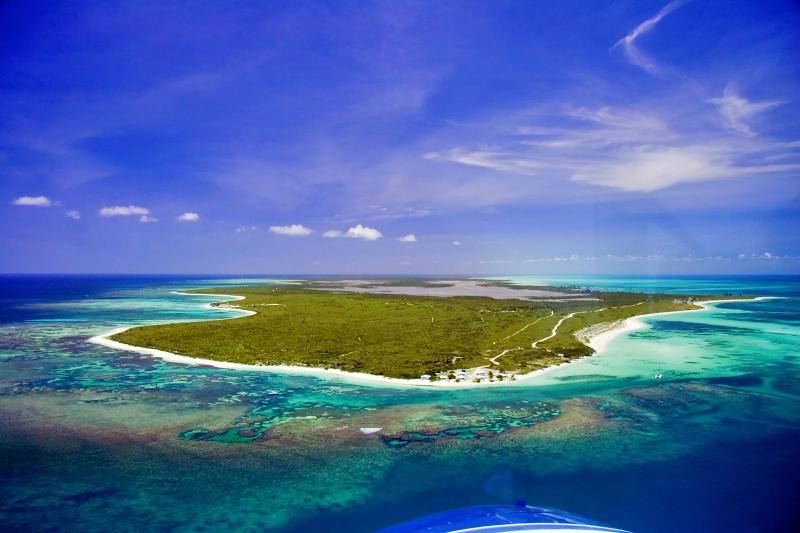Anegada's west end from the air: a low green island ringed by white sand and reef