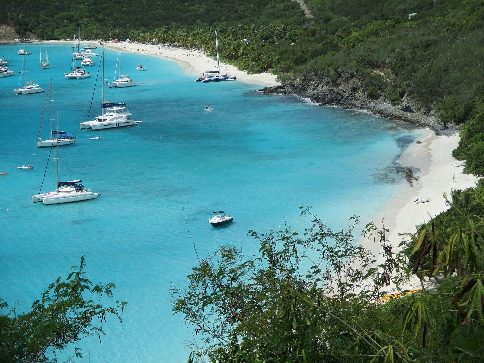 White Bay from the hill at its east end: the east beach in front, the rocky point, and the main beach beyond with boats anchored off it