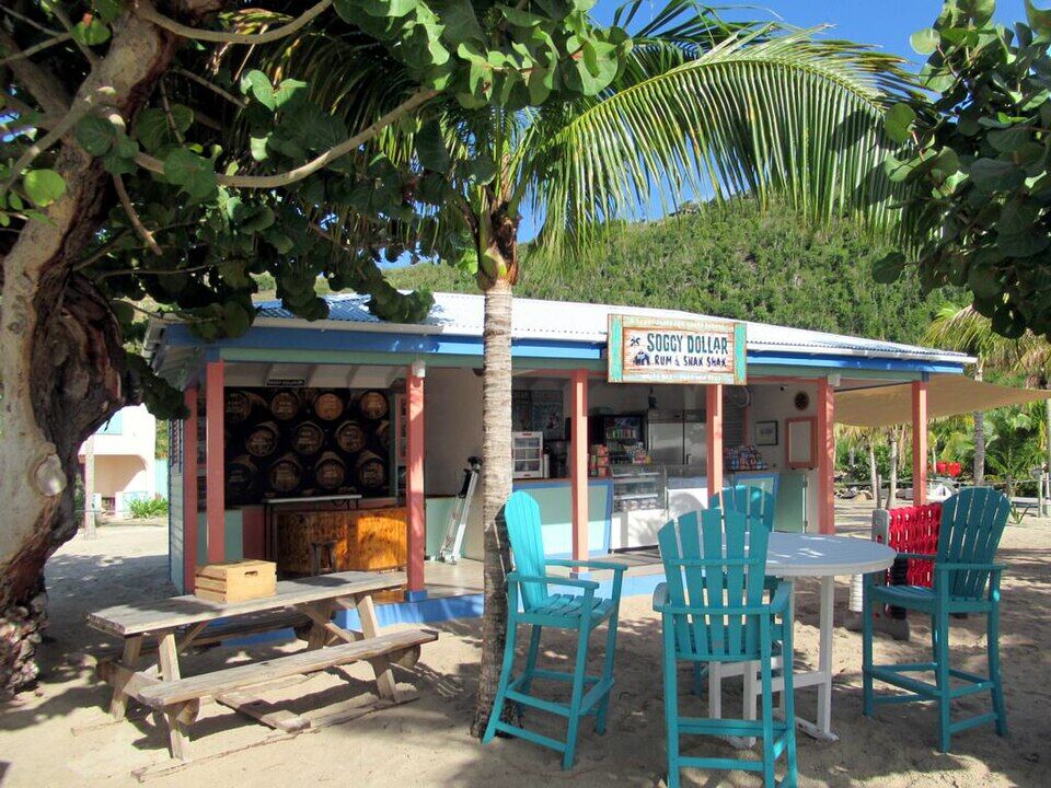 The Soggy Dollar's Rum & Shak Shak, a kiosk on the sand with rum barrels behind the counter (December 2019)