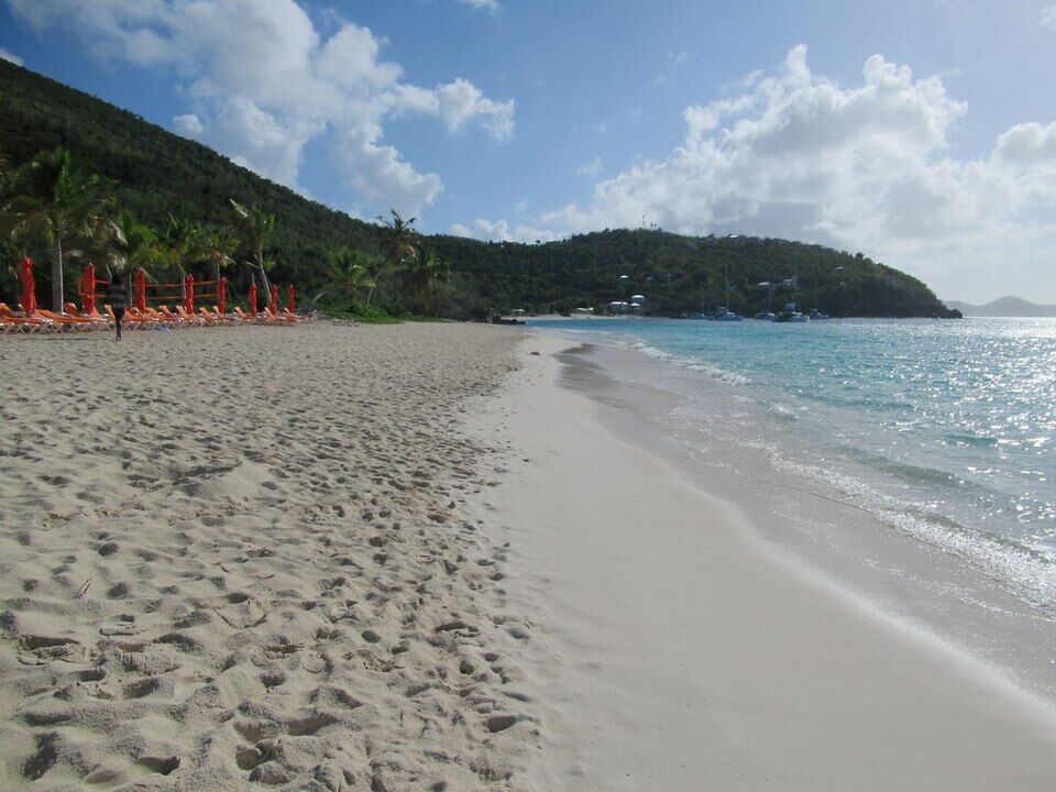 Footprints in the soft sand at the water's edge, looking east along the main beach past rows of loungers (December 2019)