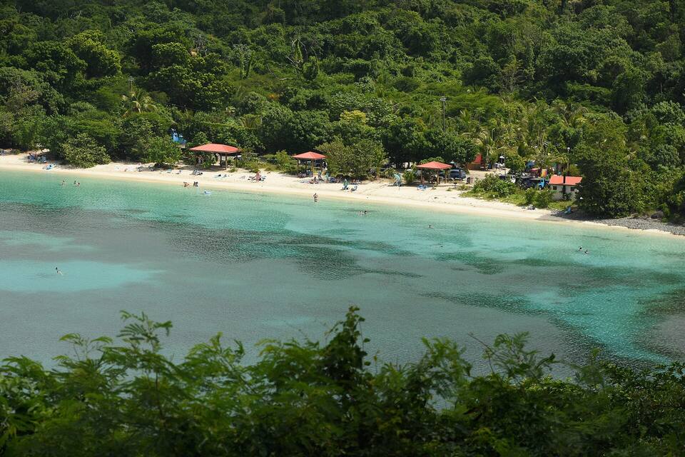 Maho Bay from the hillside: a long curve of sand under the forest