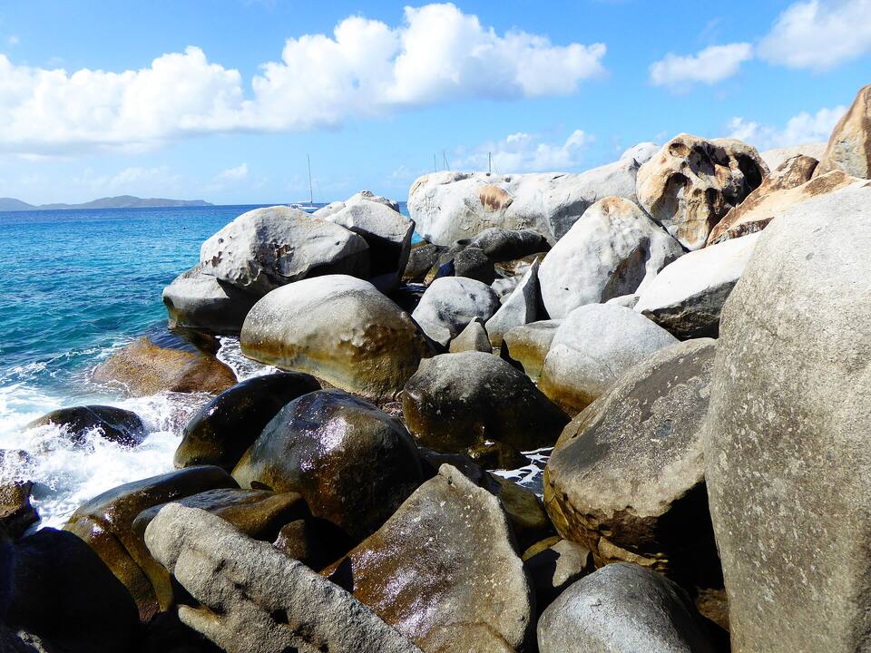 Granite boulders piled along the shore at The Baths, with the sea breaking between them